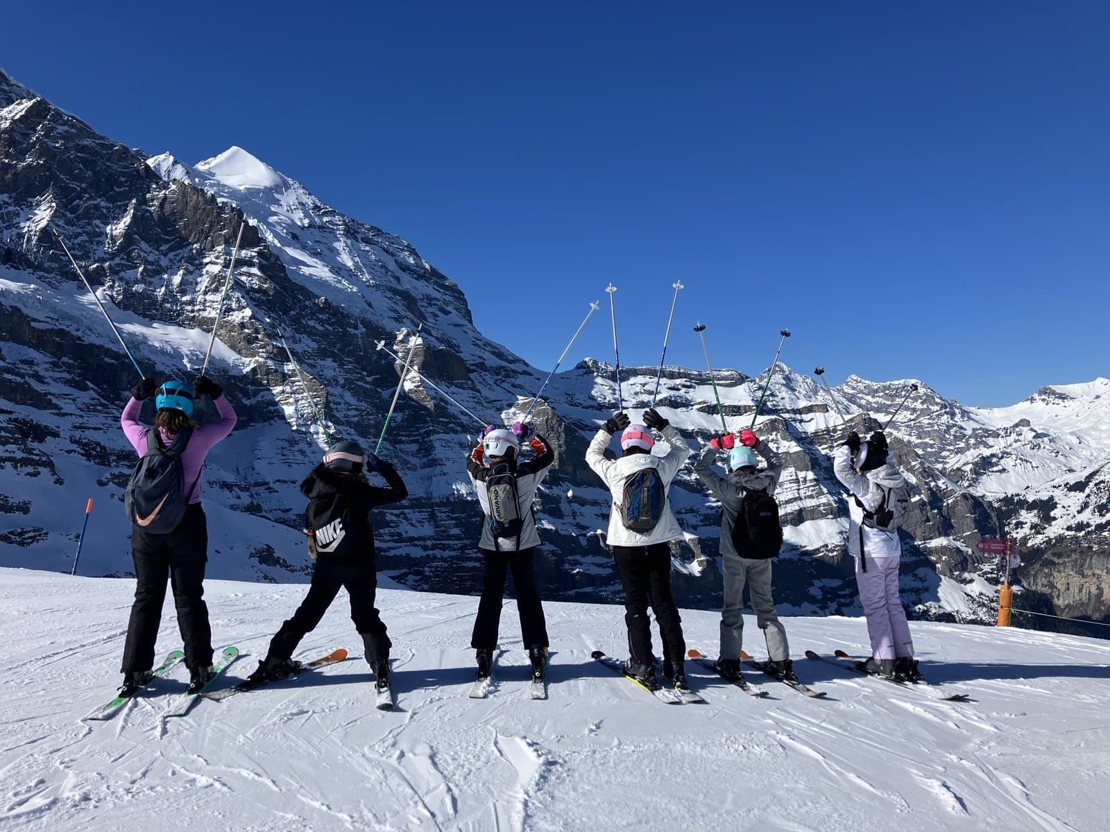 Group of young people on a snowy ridge with the Jungfrau peaks behind
